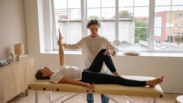 Therapist guiding a client through an assisted leg stretch on the massage table
