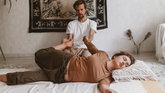 Assisted leg stretch on a floor mat during a traditional Thai massage